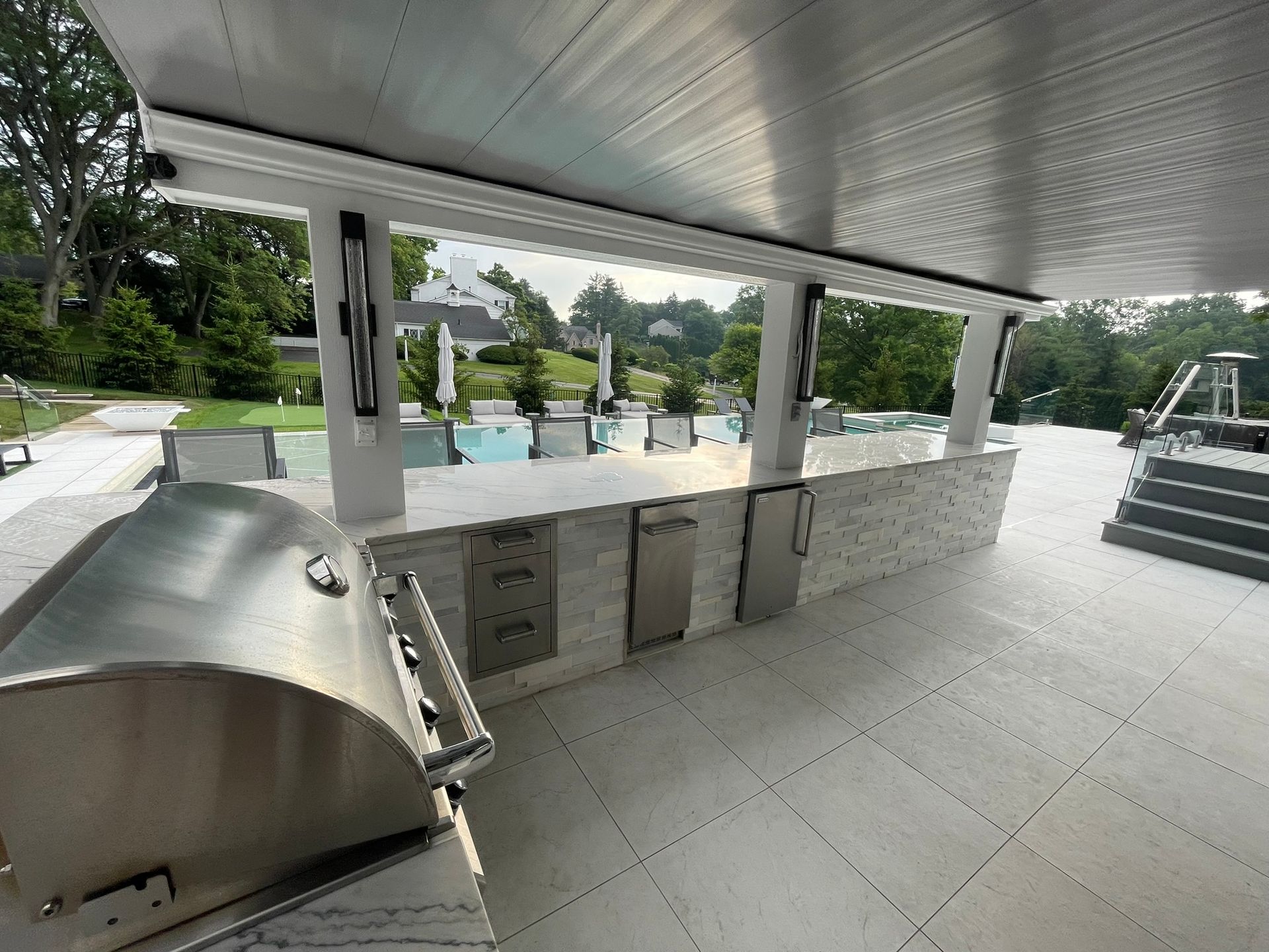 A large outdoor kitchen with a stainless steel grill