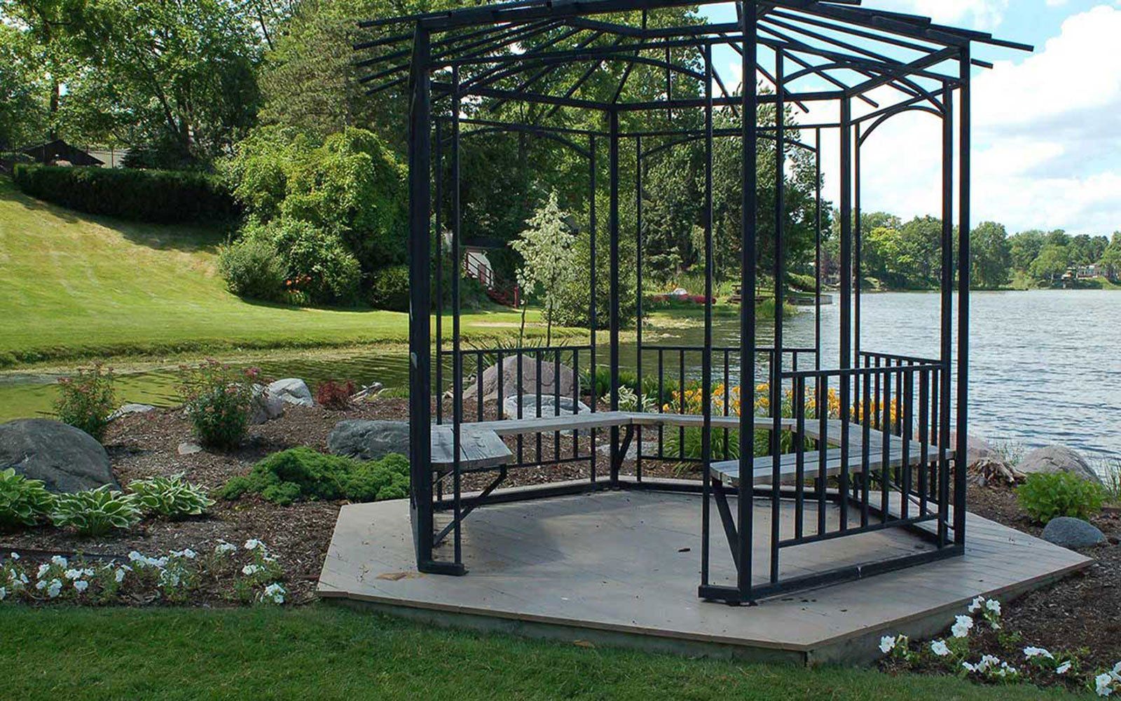 A gazebo with a table and benches in front of a lake