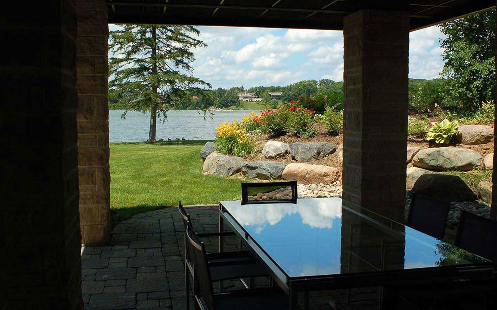 A patio with a table and chairs and a view of a lake
