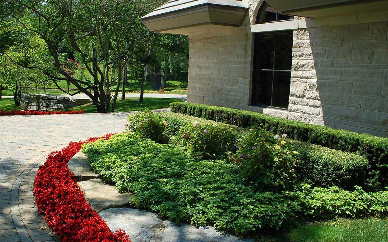 A brick building with a lush green garden in front of it