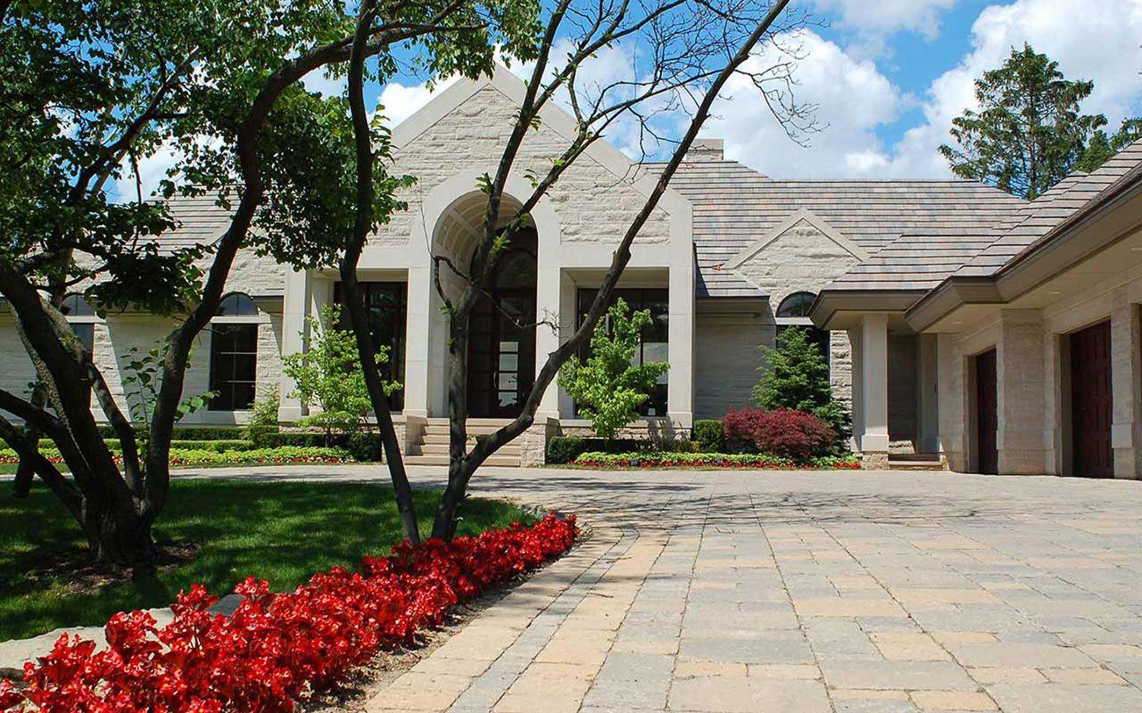 A large white house with a driveway and flowers in front of it