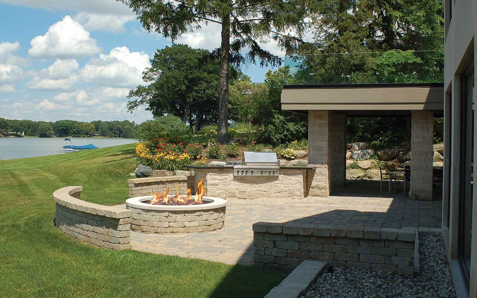 A fire pit in the backyard of a house overlooking a lake