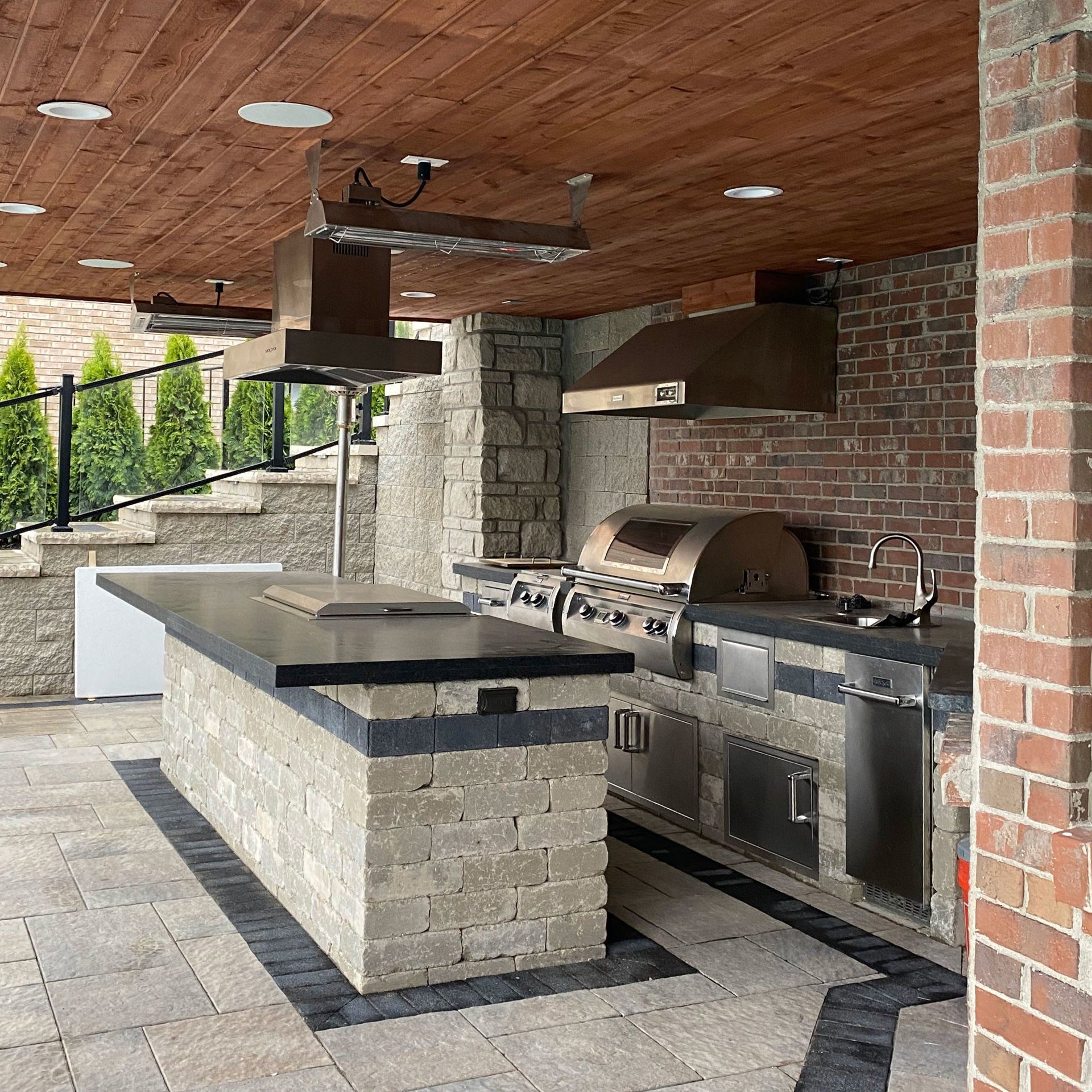 An outdoor kitchen with a brick wall and a large island