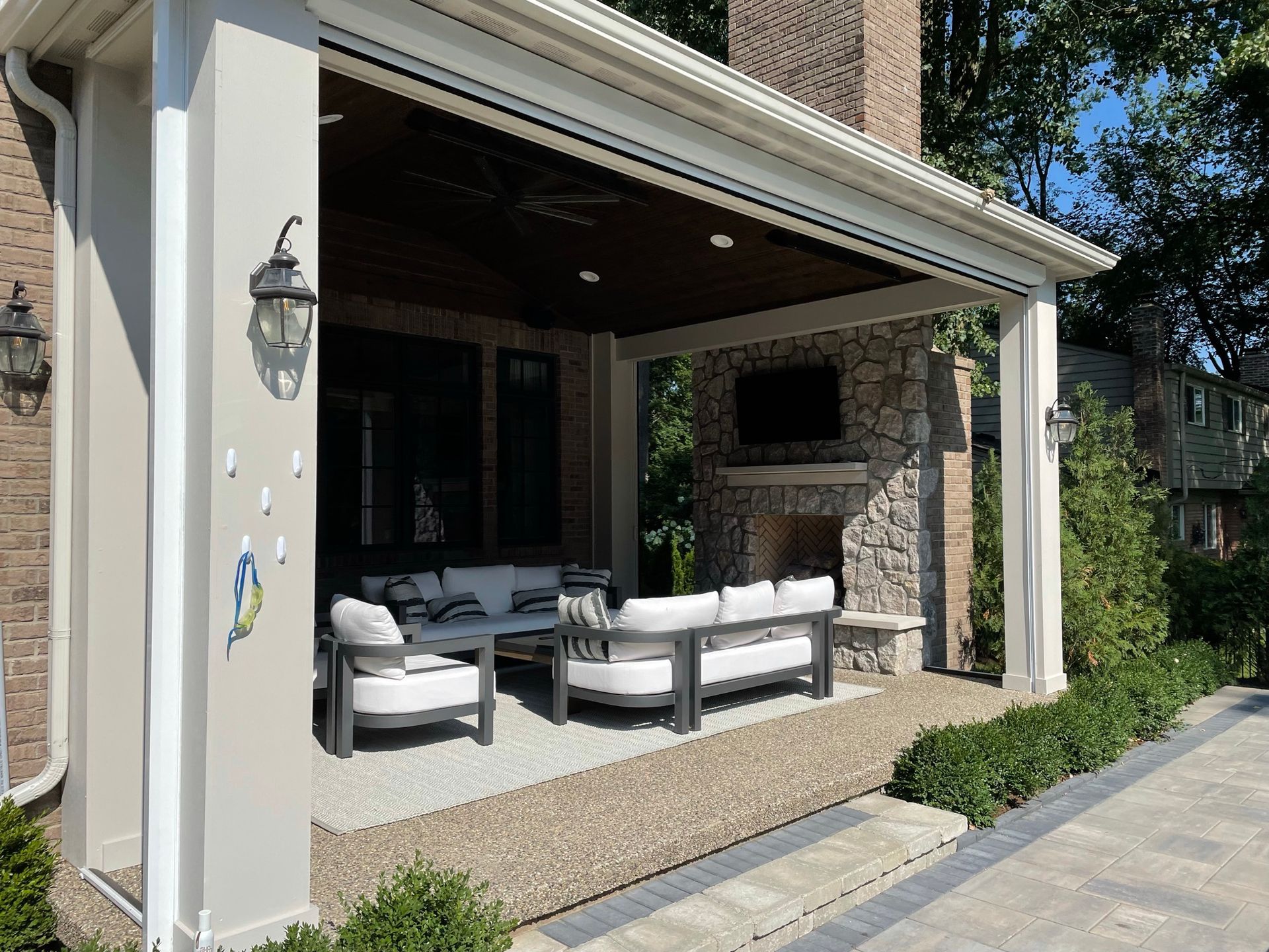 A patio with a fireplace and a couch and chairs under a covered porch.