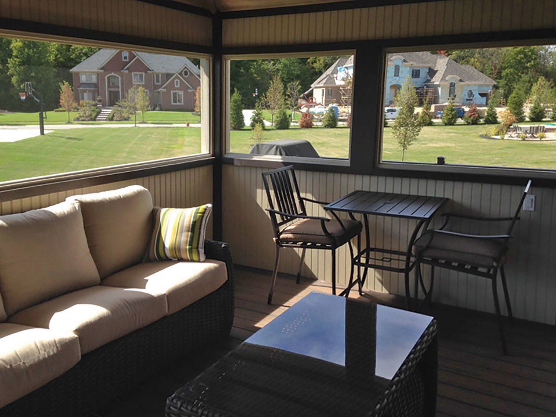 a screened in porch with a couch table and chairs