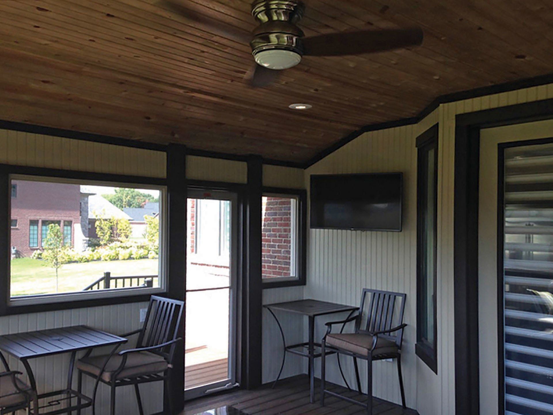 a screened in porch with a table and chairs and a ceiling fan .