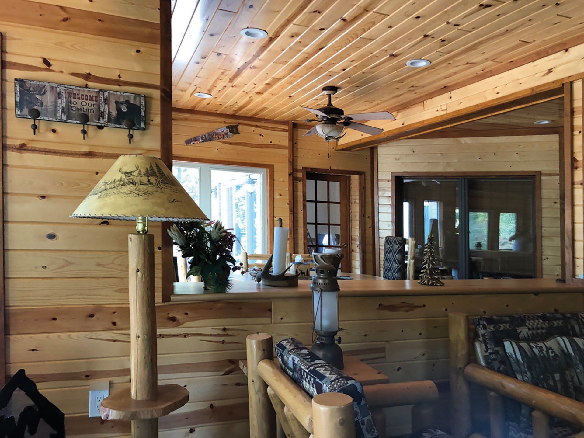 a living room in a log cabin with a ceiling fan and a lamp .