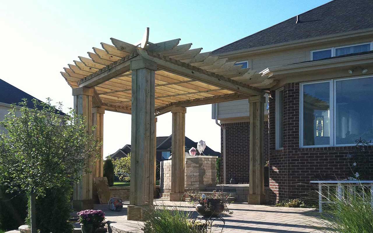 a wooden pergola is sitting in front of a brick house .
