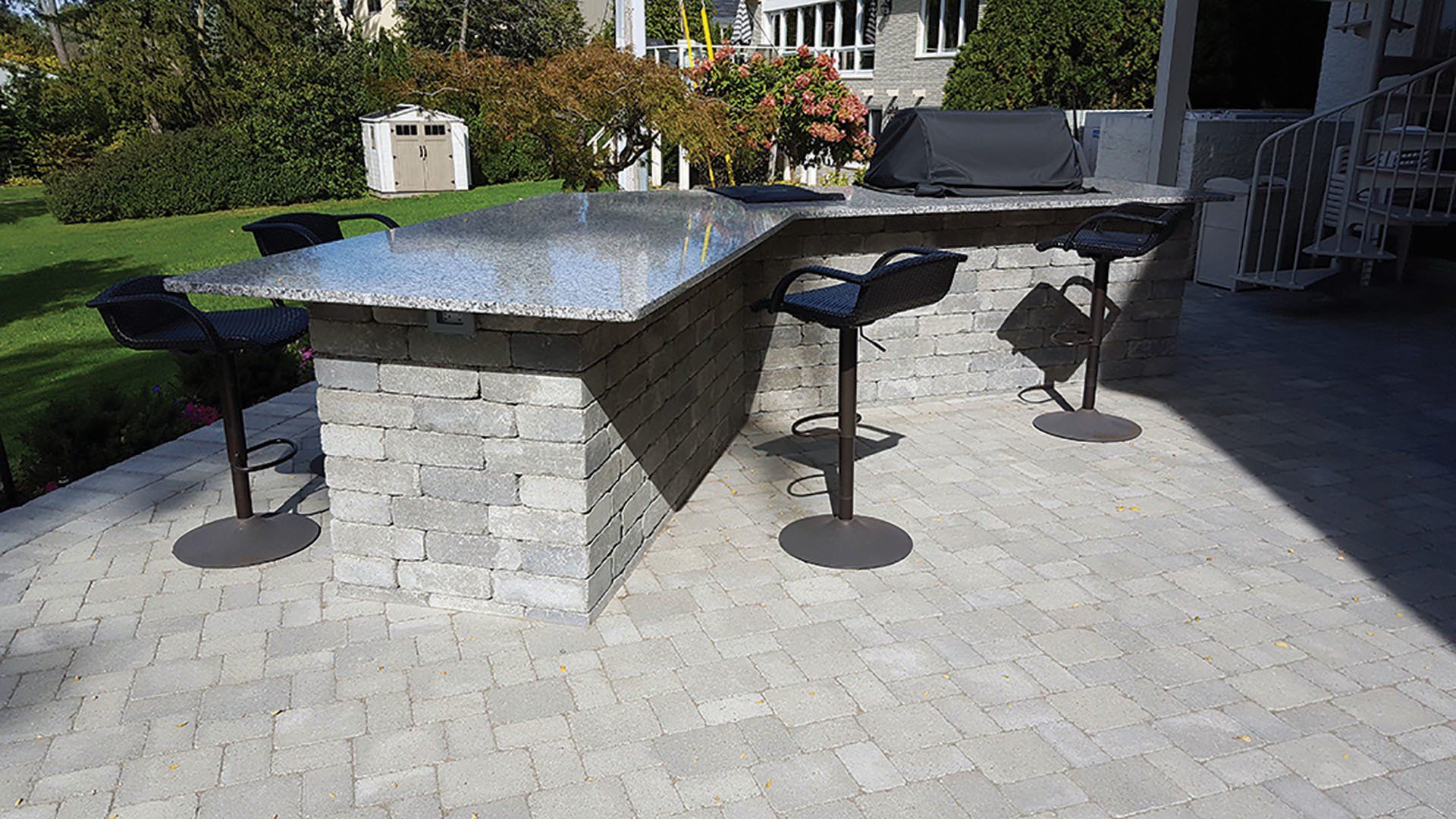 a patio with a bar and stools and a grill .