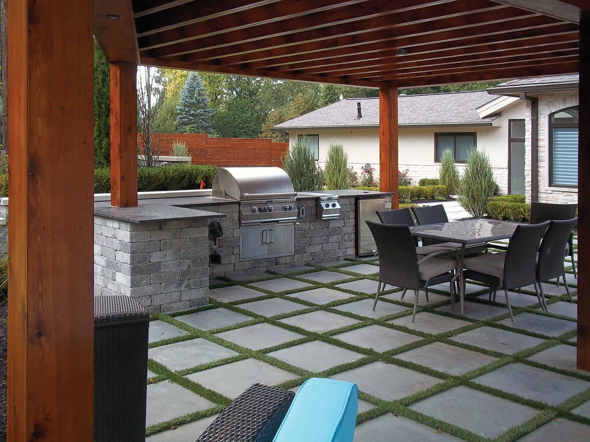 a patio with a table and chairs and a grill under a pergola