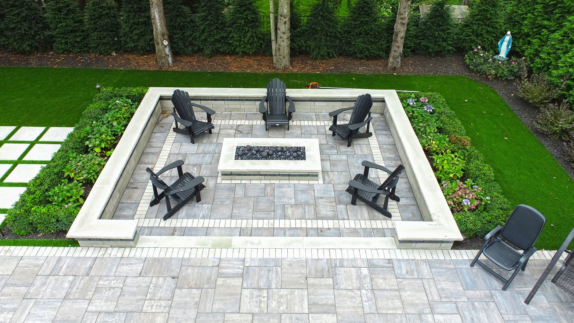 an aerial view of a patio with a fire pit and chairs .