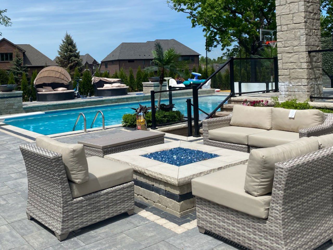 a patio with wicker furniture and a fire pit in front of a swimming pool .