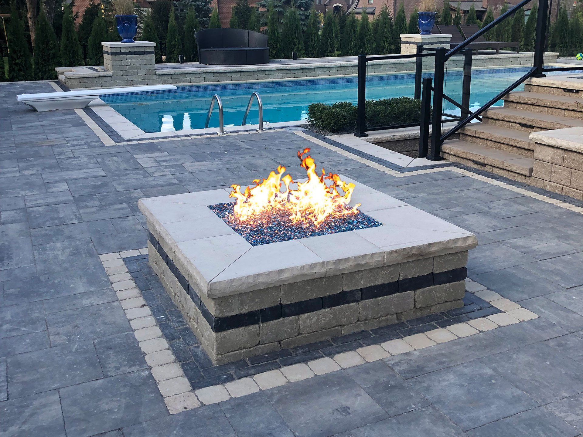 a fire pit is sitting on a patio next to a pool .