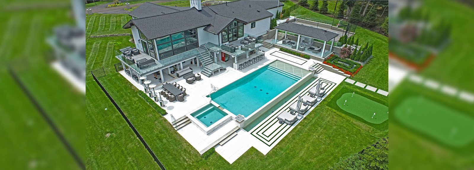 An aerial view of a large house with a swimming pool and a putting green.