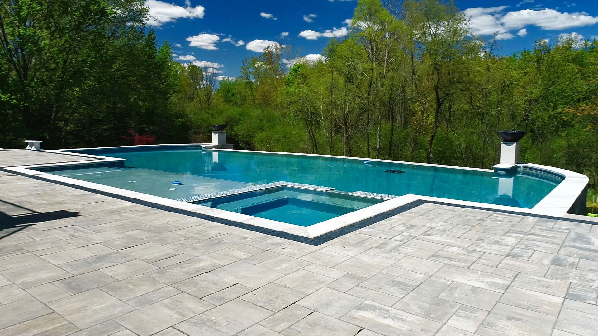 a large swimming pool is surrounded by trees on a sunny day