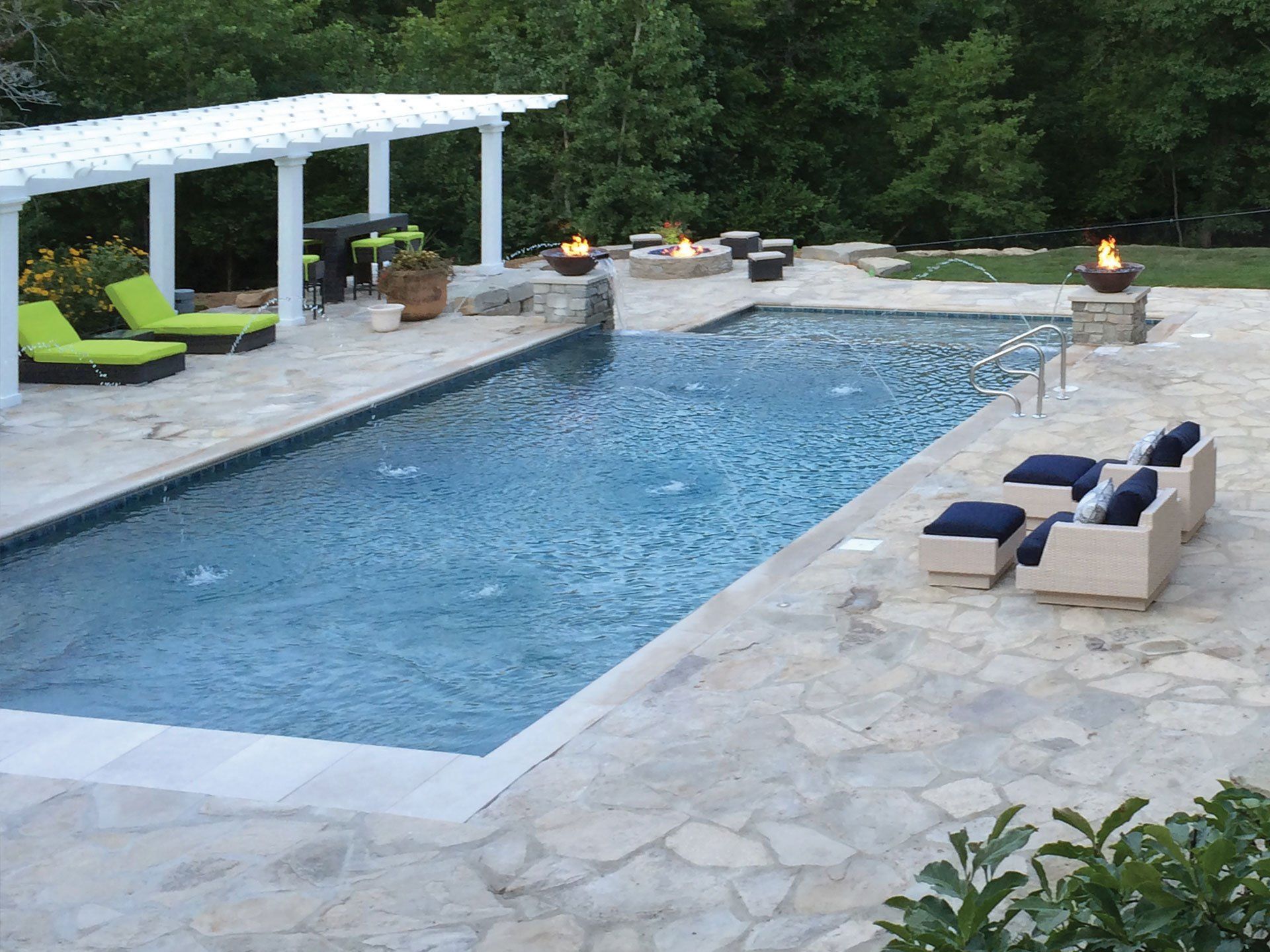 a large swimming pool surrounded by chairs and a pergola