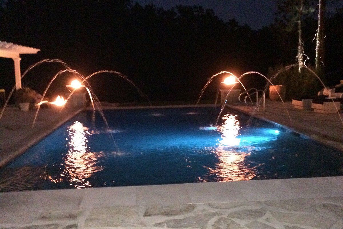 a large swimming pool is lit up at night