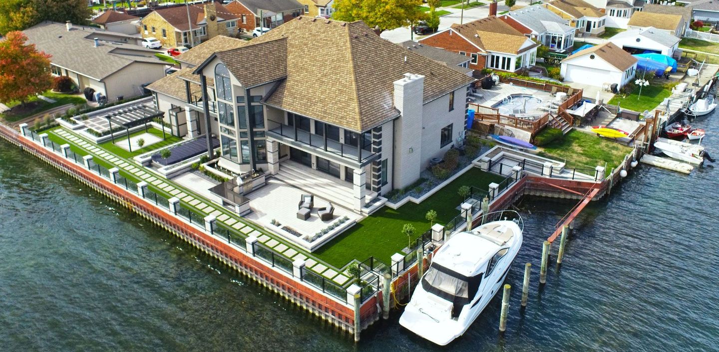 An aerial view of a large house on a small island in the middle of a body of water.