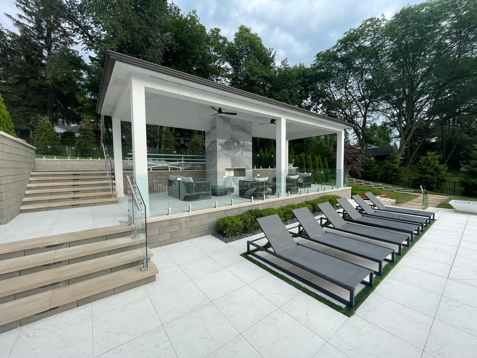 A row of lounge chairs are lined up in front of a gazebo.