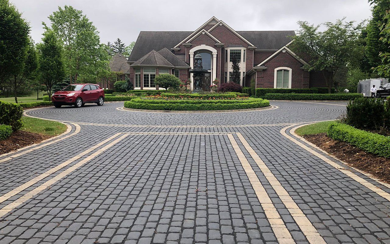 Brick driveway in front of a large house .