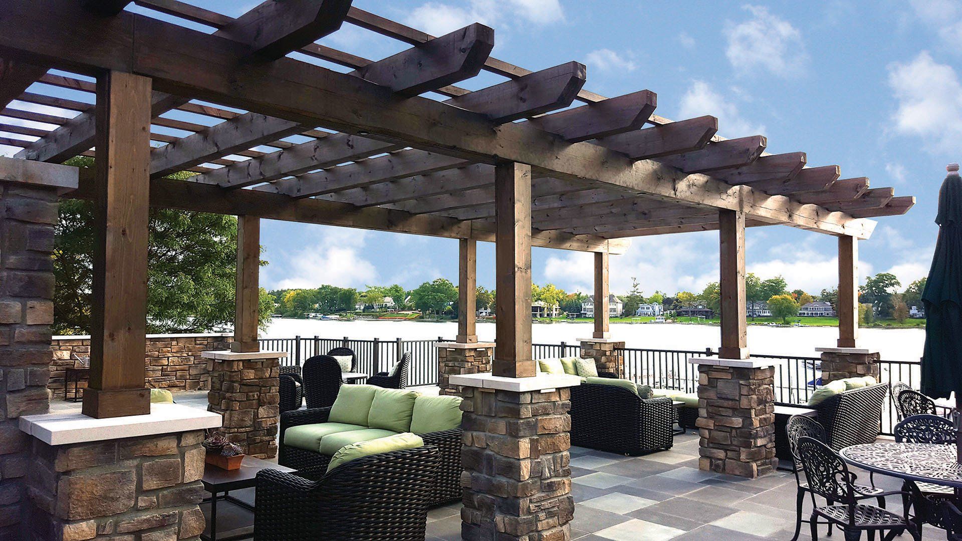 a patio with a pergola and a lake in the background