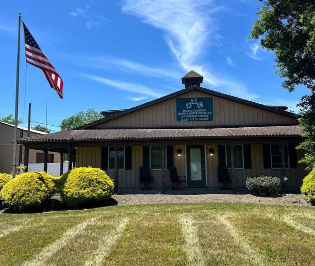 Small wooden building with a porch and U.S. flag under a bright blue sky