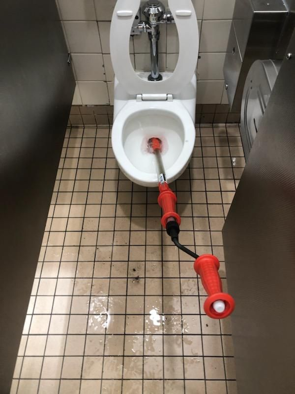 Restroom with a toilet and a red emergency suction device on the floor and in the bowl