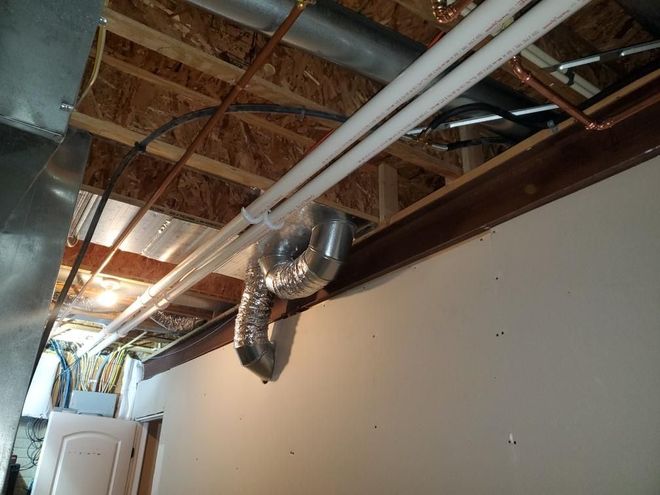 Exposed attic ceiling with ducts, pipes, and wooden beams in an unfinished interior