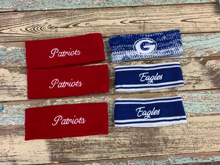 A group of headbands with the words patriots and eagles on them are sitting on a wooden table.