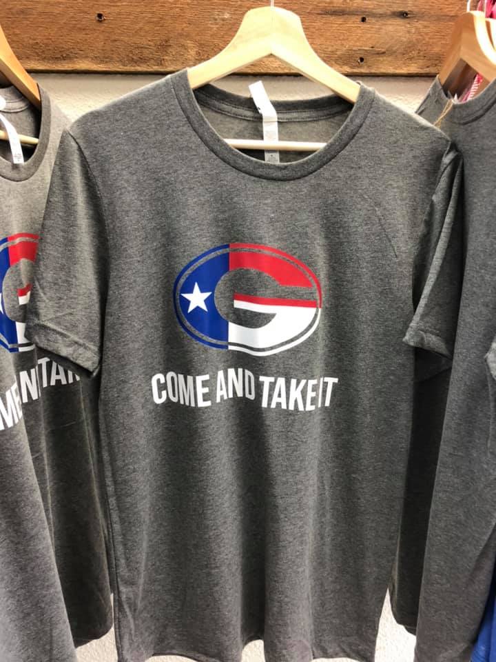 A t-shirt that says come and take it is hanging on a hanger.