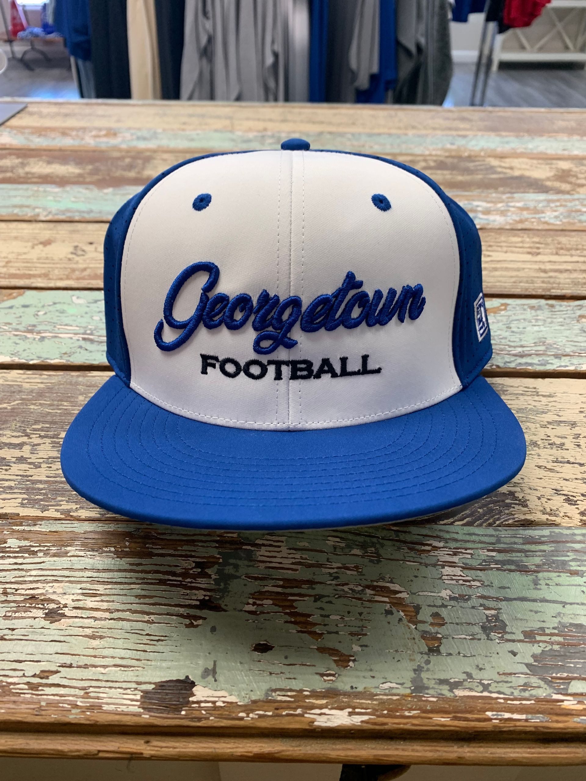 A blue and white georgetown football hat is sitting on a wooden table.