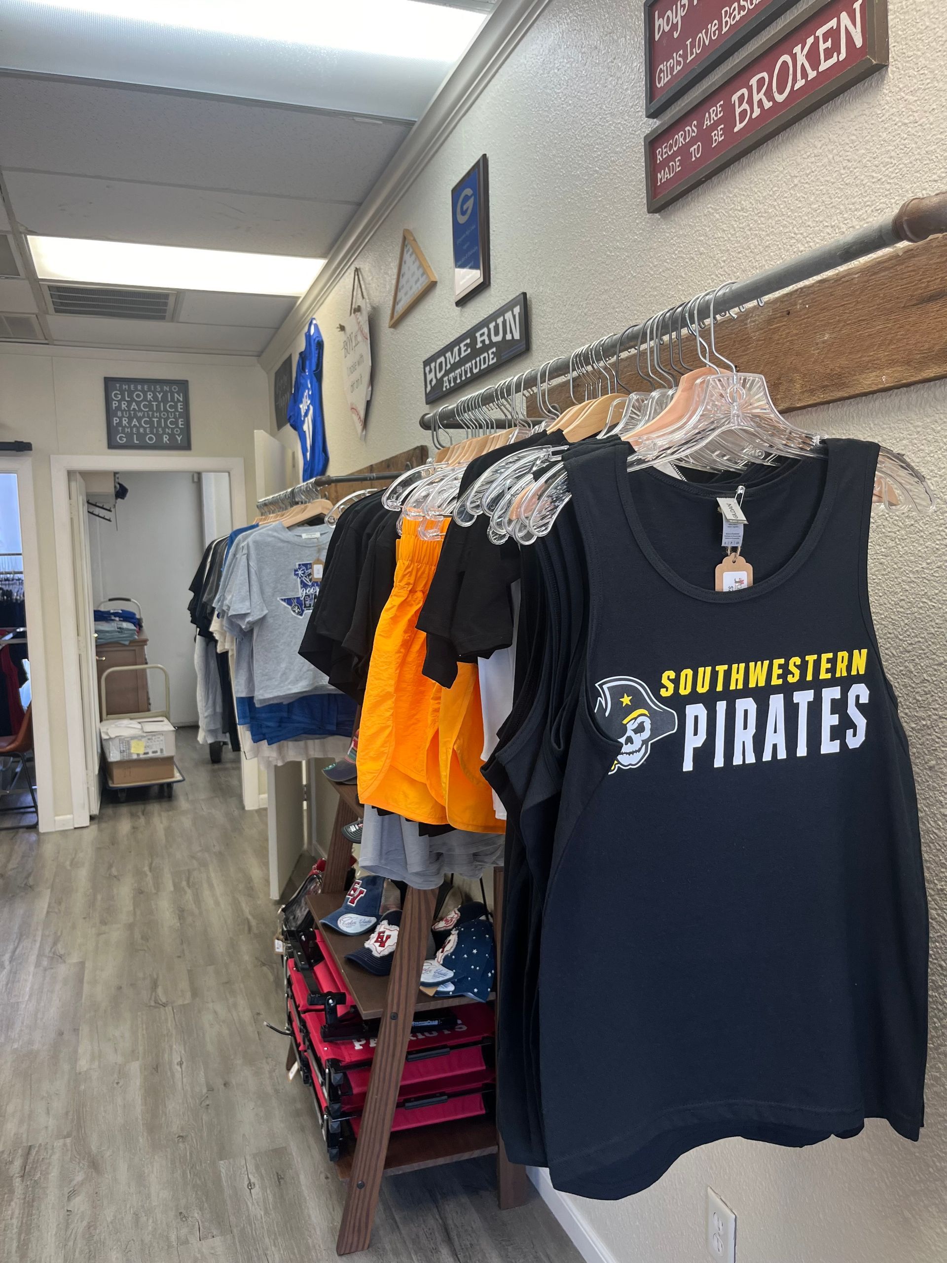 A row of shirts hanging on a rack in a store with one that says pirates on it.