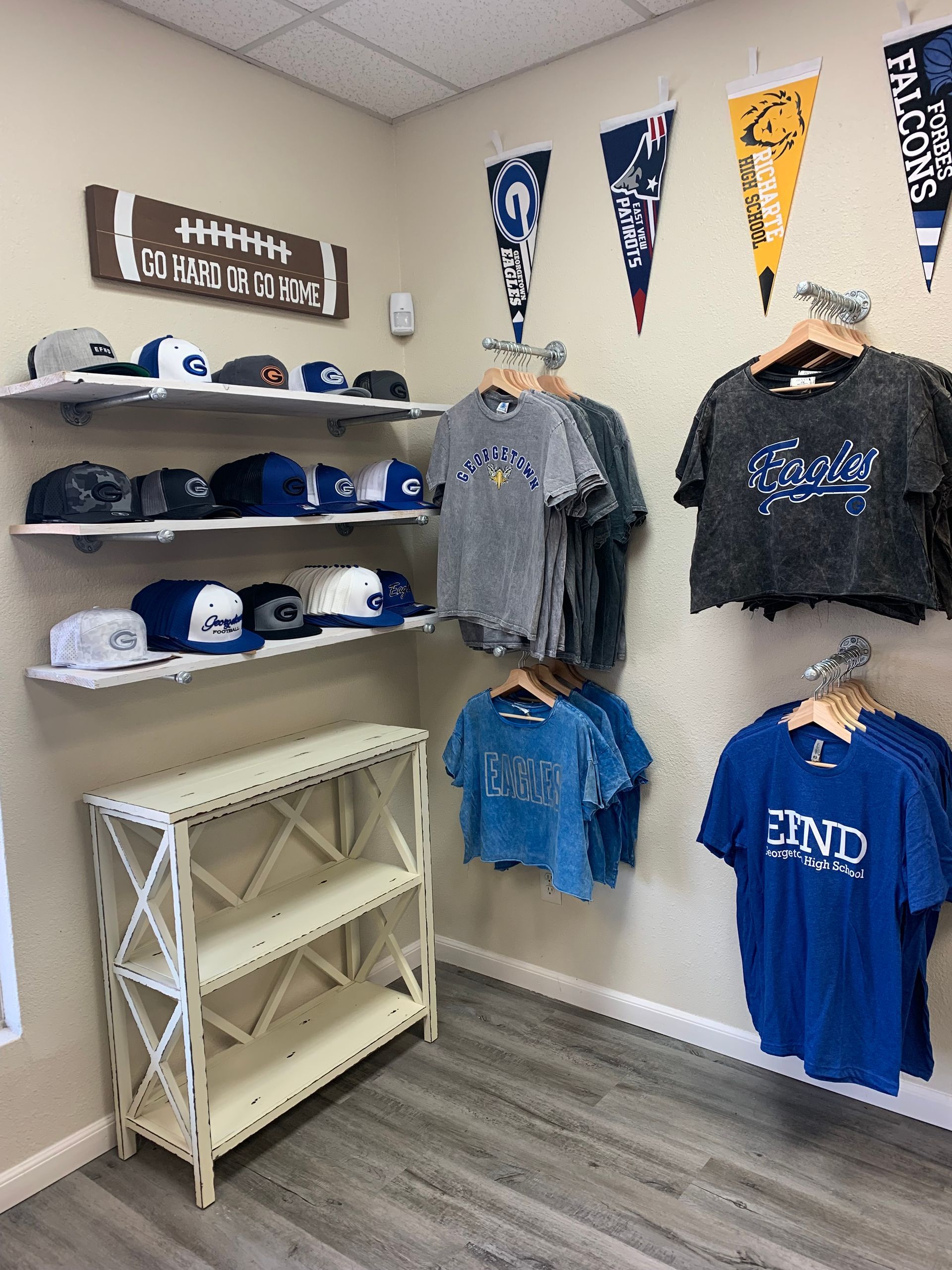 A room with a lot of shirts and hats hanging on the wall.