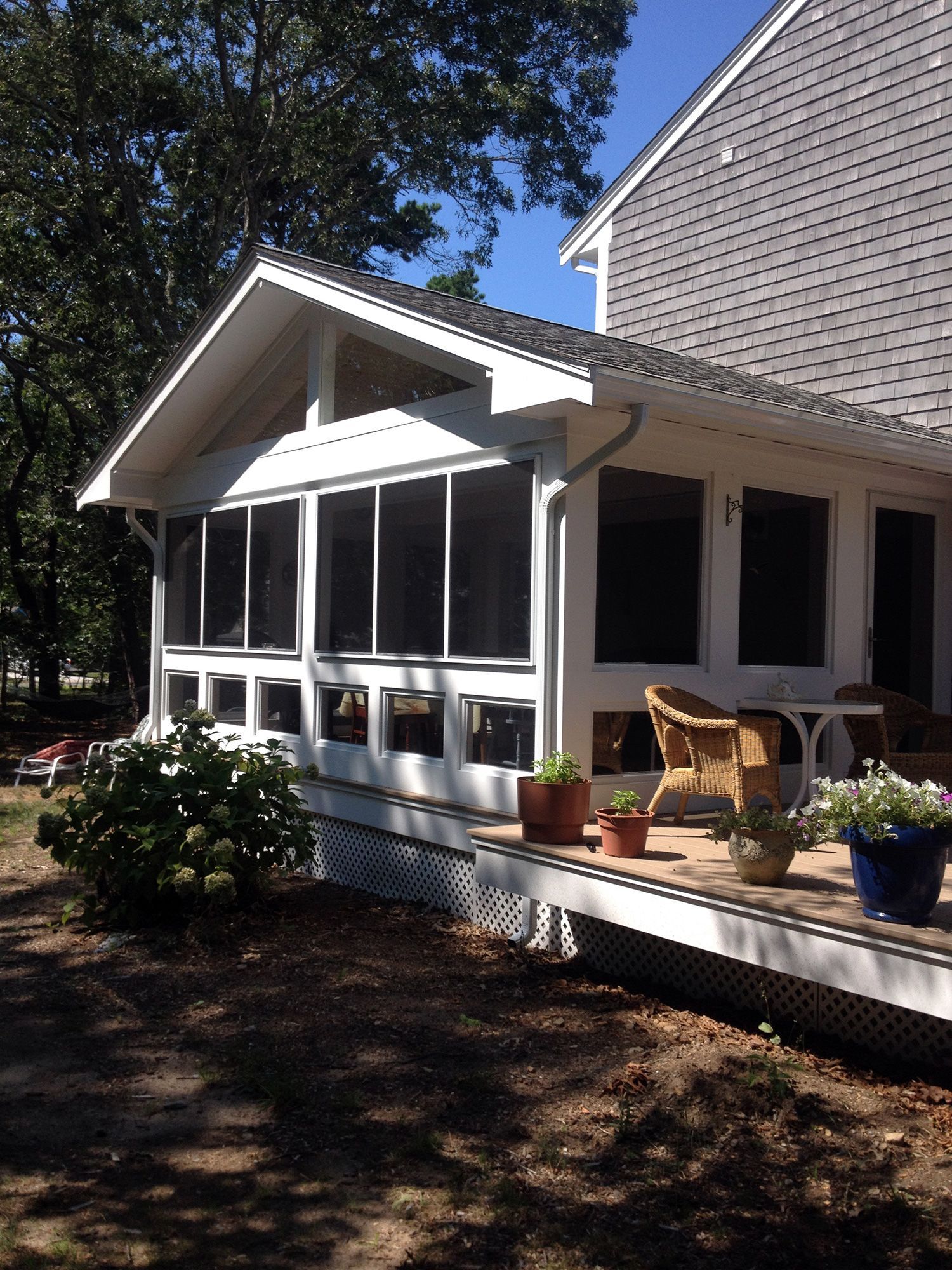 a screened in porch with chairs and potted plants