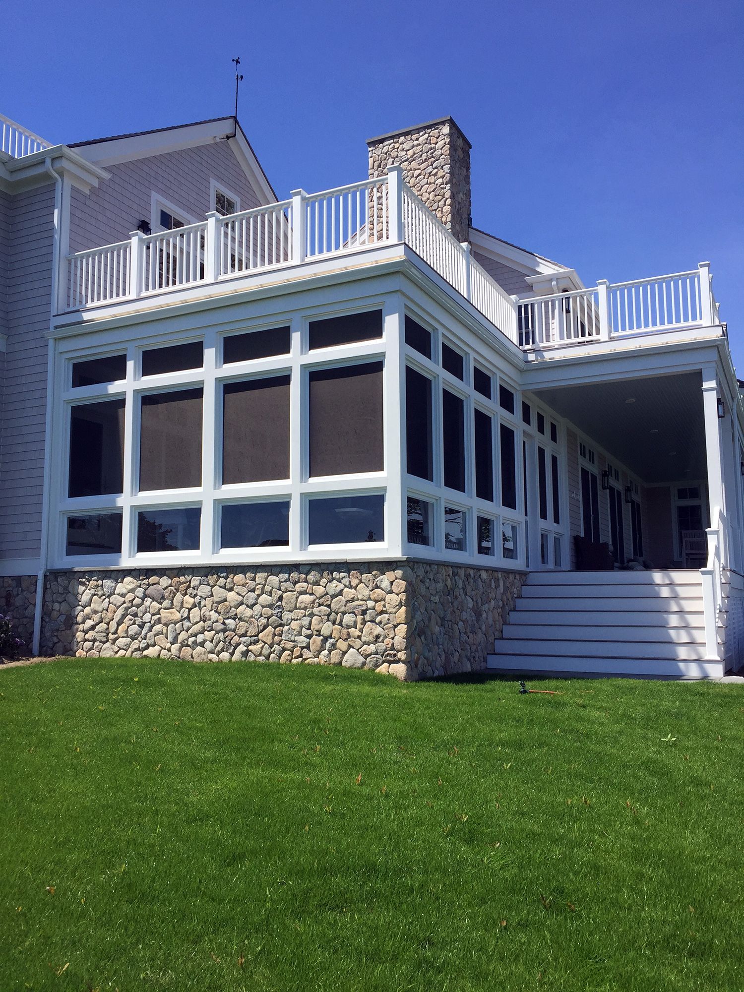 the back of a large house with a screened in porch and stairs