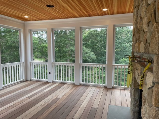 a screened in porch with lots of windows and a fireplace