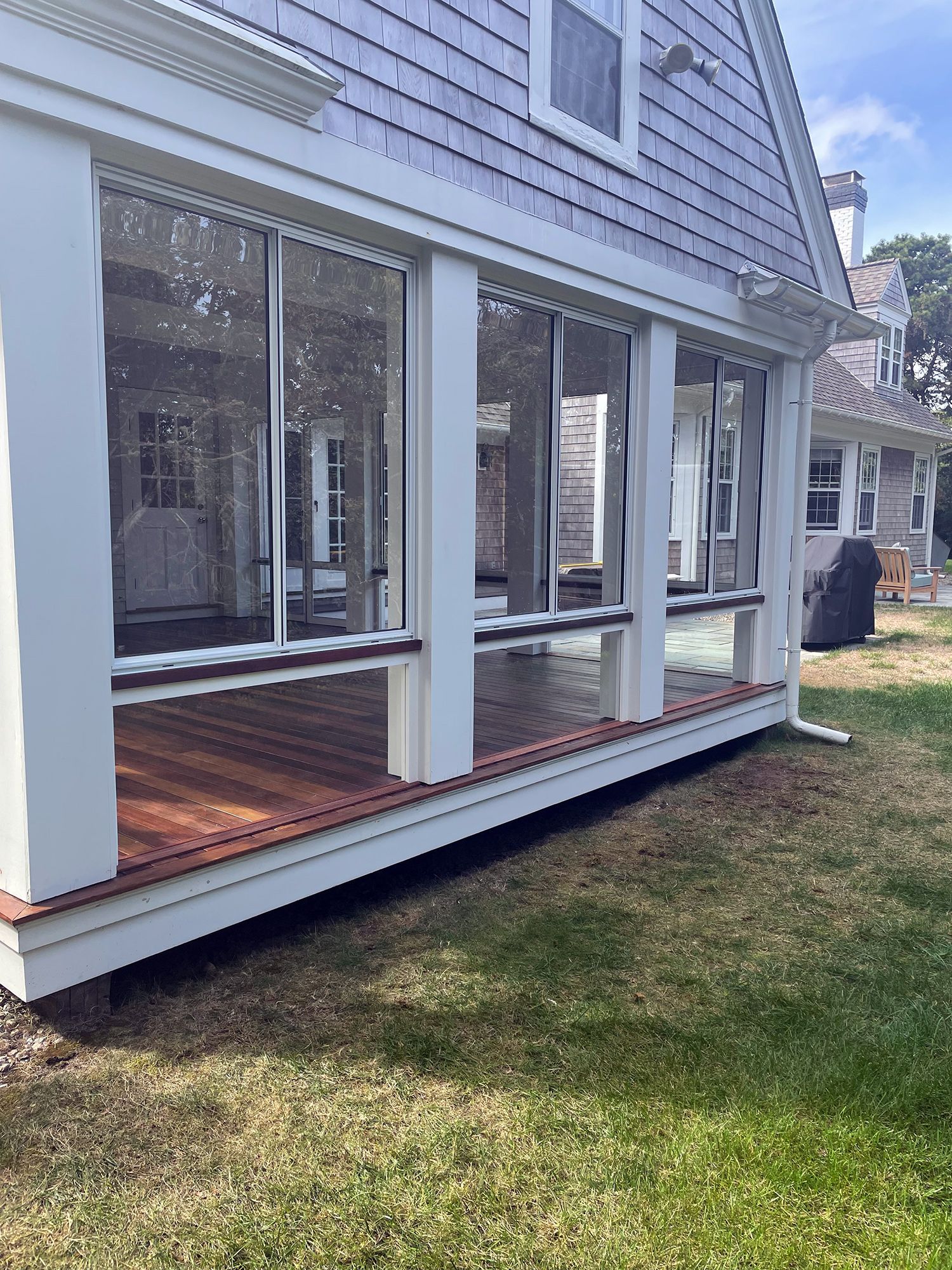 a screened in porch with a lot of windows on the side of a house