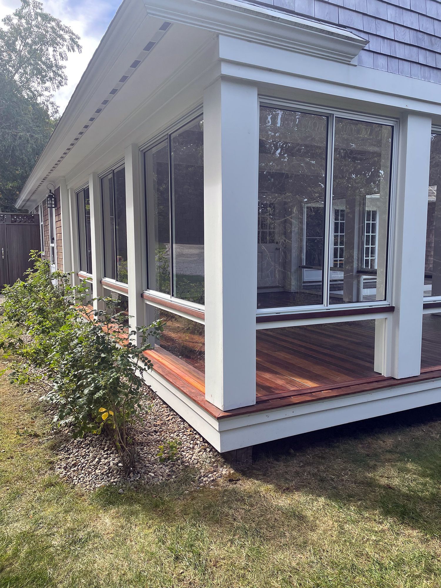 a screened in porch with a lot of windows and a wooden deck