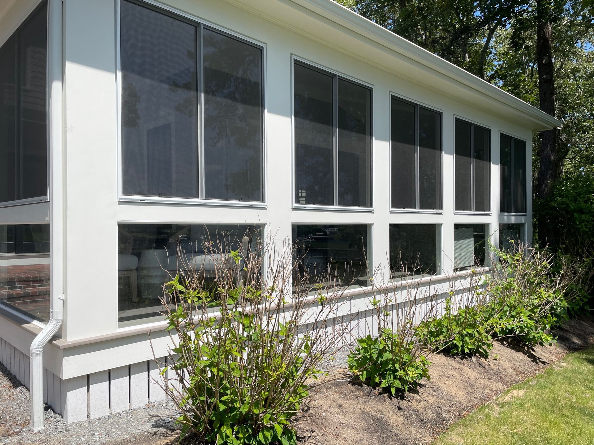 a white house with a screened in porch and lots of windows