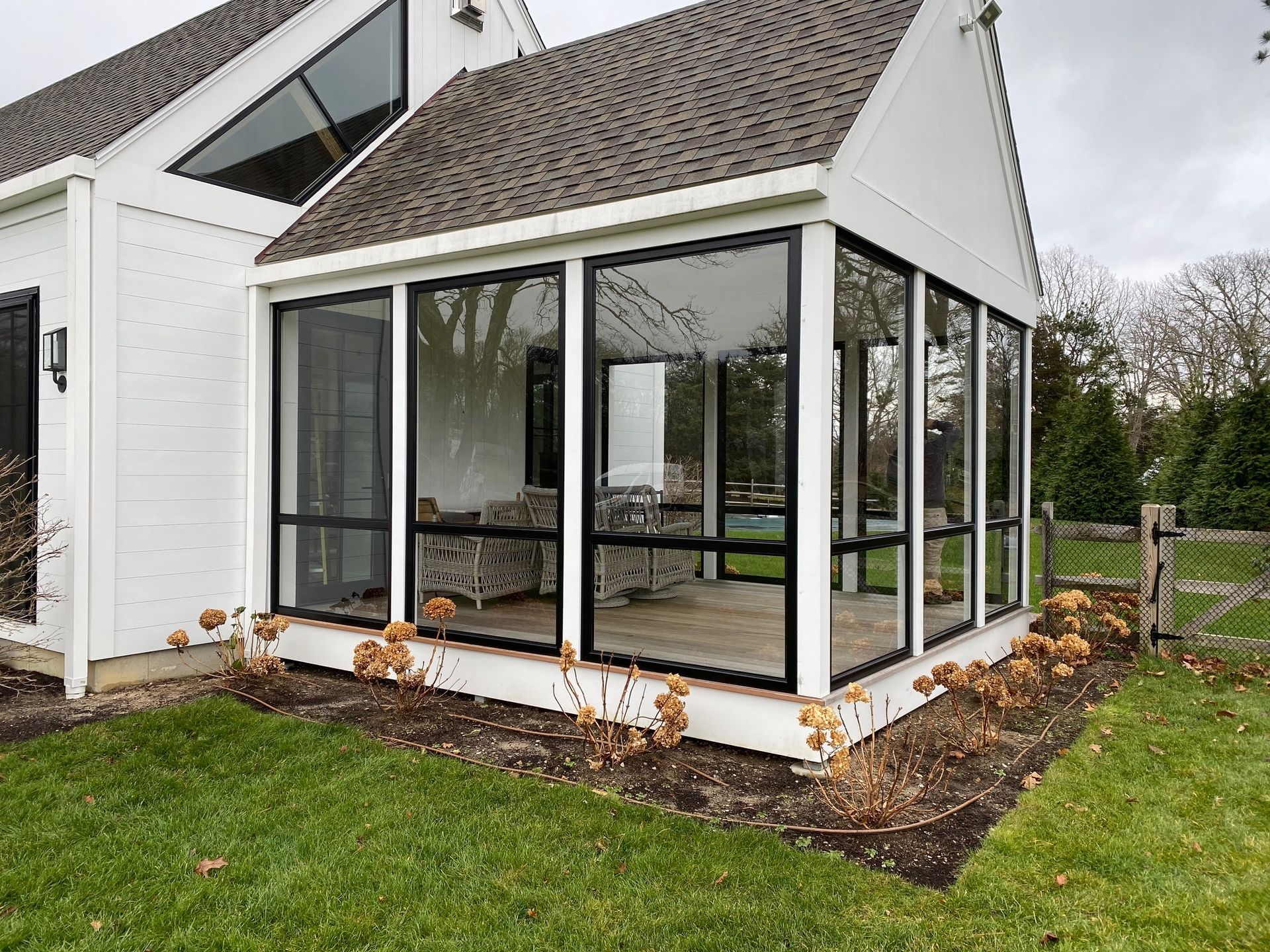 a screened in porch with a lot of windows on the side of a house