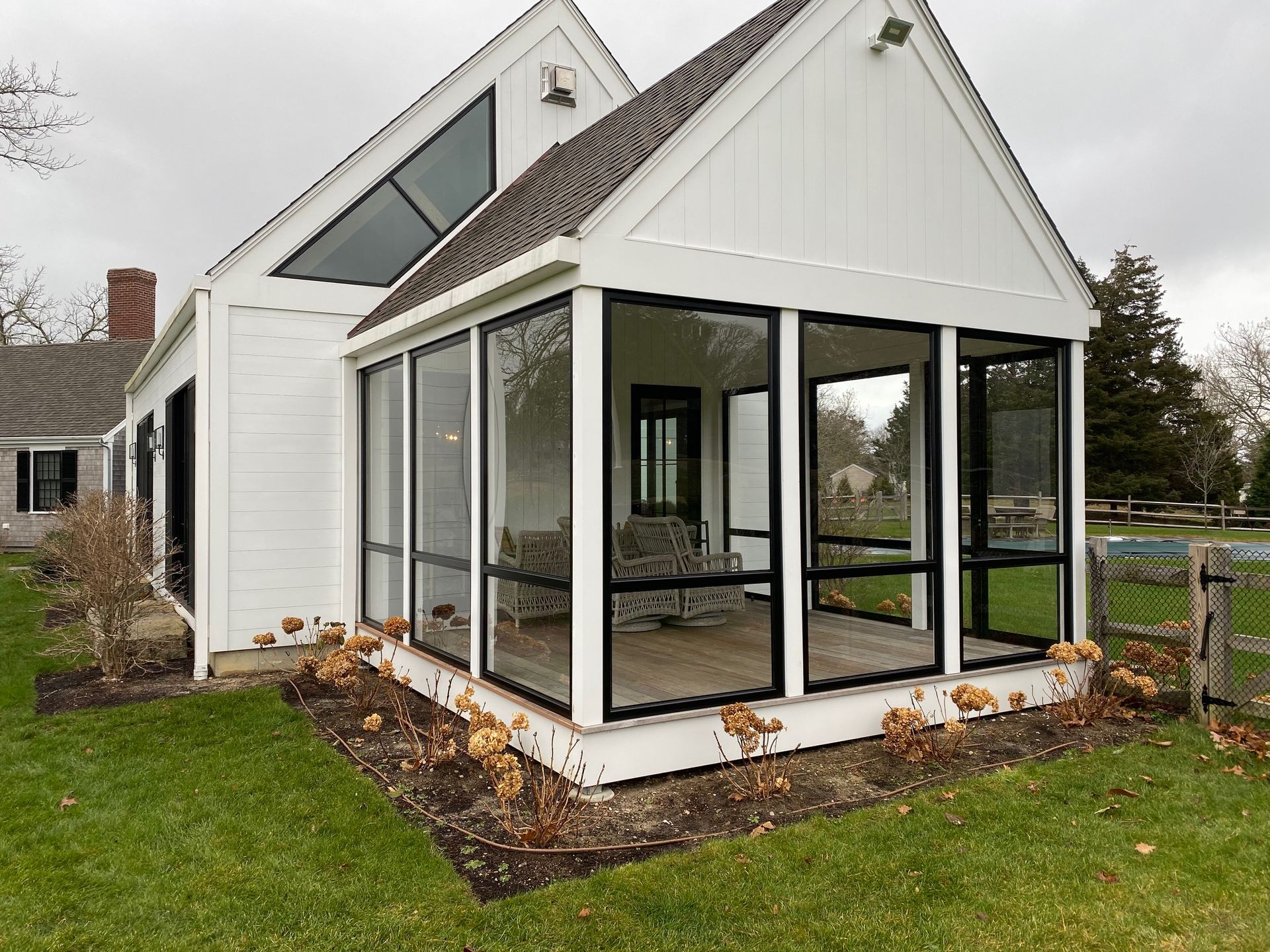 a white house with a screened in porch in the backyard