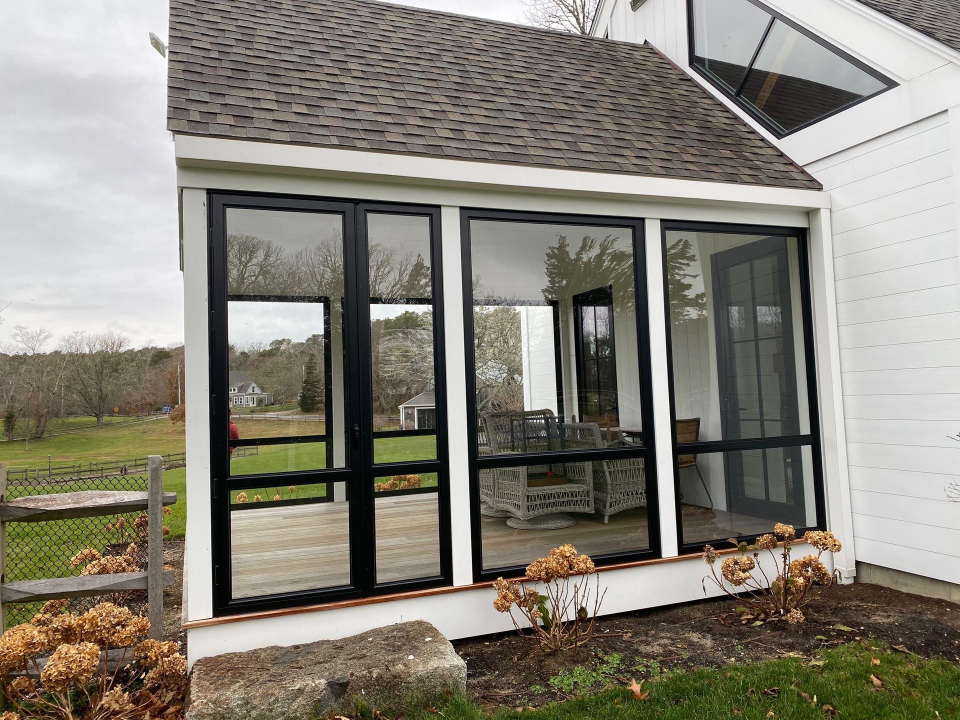 a white house with a screened in porch with black windows