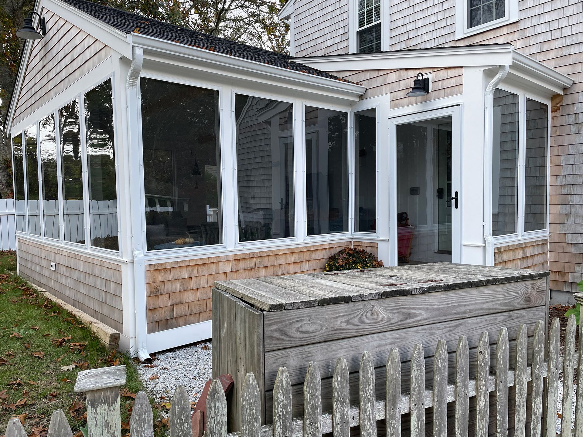 a screened in porch with a wooden fence in front of it