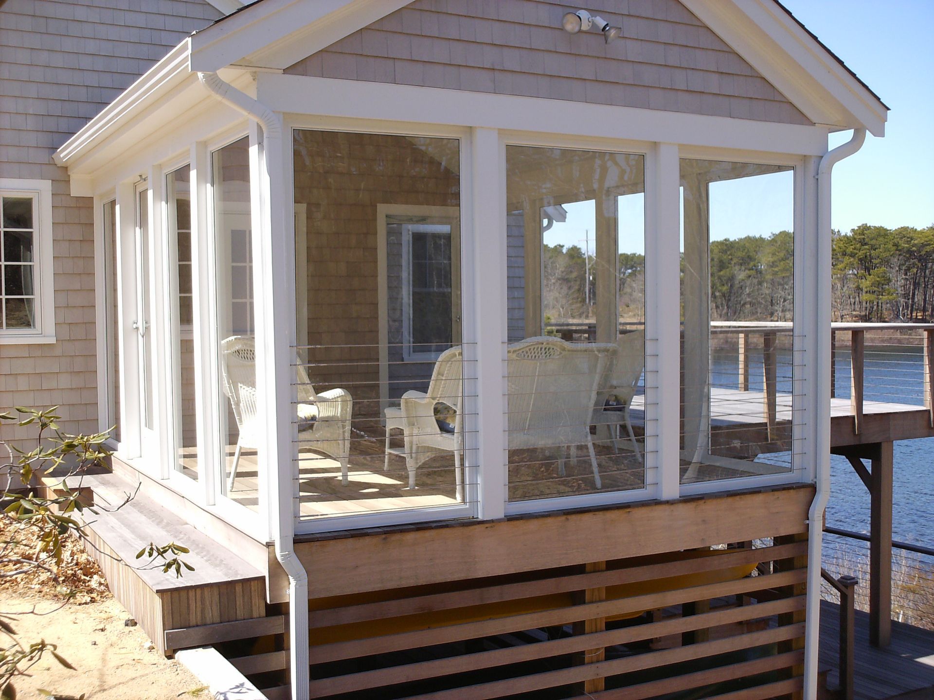 a house with a screened in porch overlooking a body of water