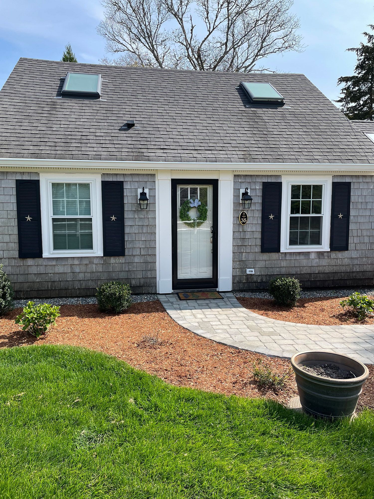 a small house with black shutters and a skylight on the roof