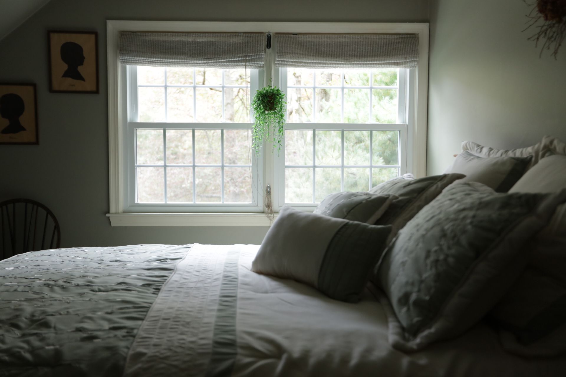 a bed with white sheets and pillows is in front of a window in a bedroom