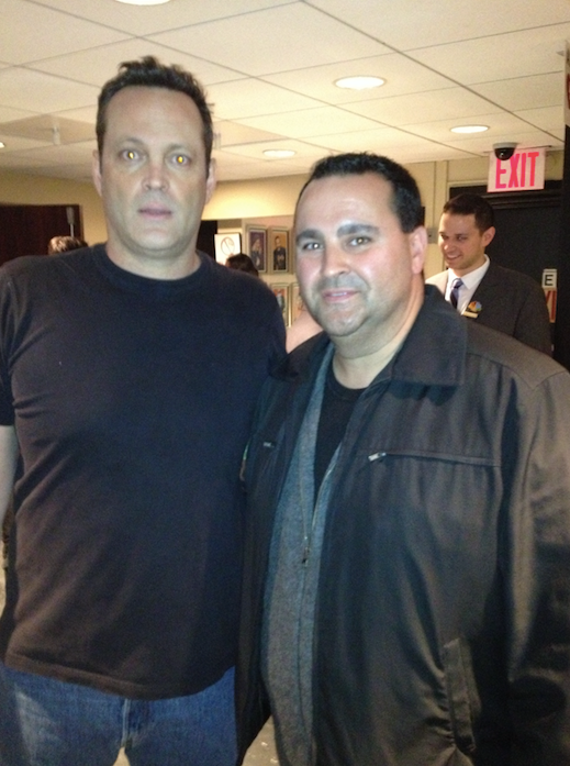 Vince Vaughn and a man pose together, both smiling. They stand near an exit sign.