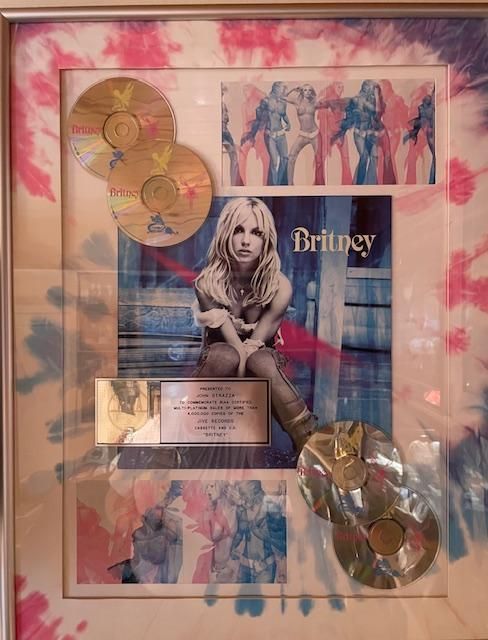 Framed Britney Spears album award with gold CDs and tie-dye border.