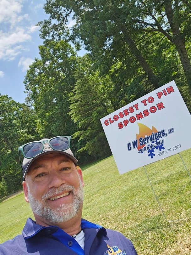 Smiling man taking selfie beside a sign in a grassy park