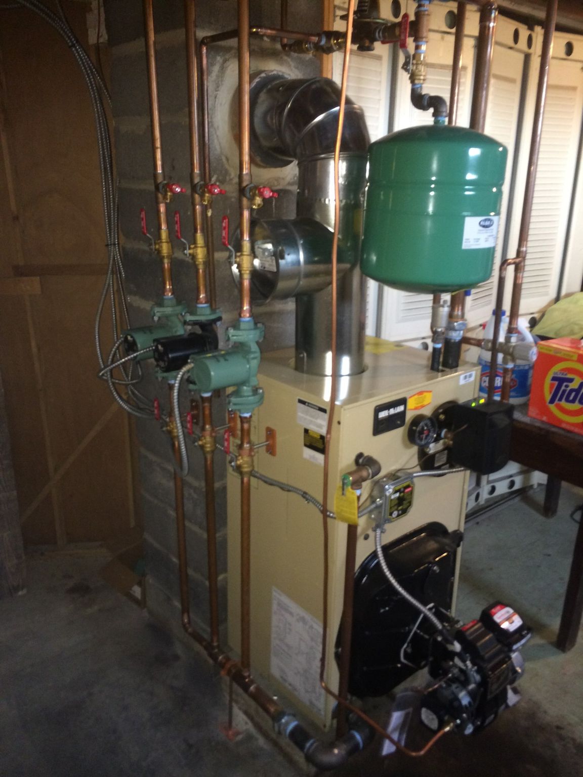 Boiler room with water heater, pipes, and a green expansion tank beside a furnace unit